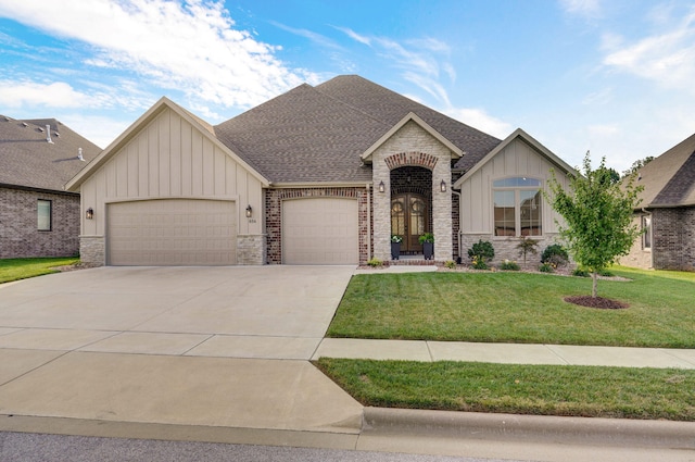 view of front of property with an attached garage, a shingled roof, driveway, board and batten siding, and a front yard