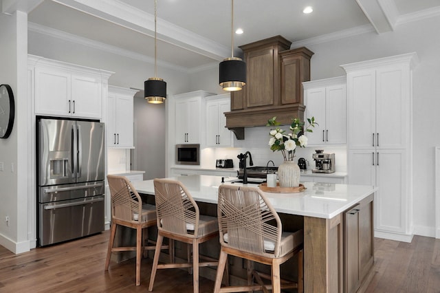 kitchen with an island with sink, appliances with stainless steel finishes, wood finished floors, light countertops, and backsplash