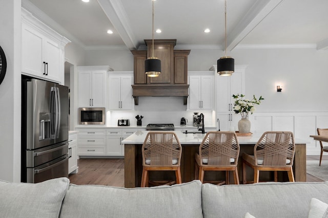 kitchen with a breakfast bar, appliances with stainless steel finishes, light countertops, and beam ceiling