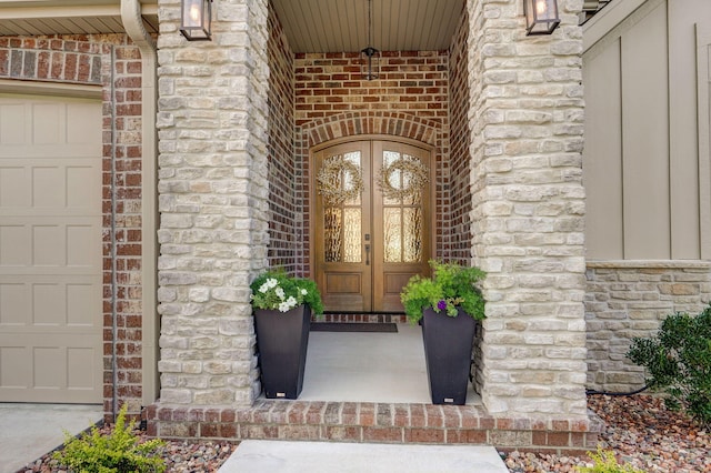 property entrance with stone siding, french doors, an attached garage, and brick siding