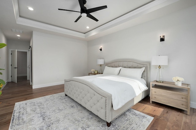 bedroom with baseboards, a tray ceiling, wood finished floors, and recessed lighting