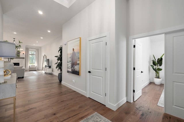 hallway with baseboards, wood finished floors, and recessed lighting