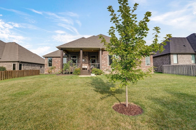 rear view of property featuring a yard, brick siding, and fence