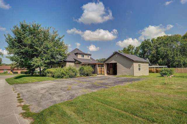 view of front of house featuring aphalt driveway, fence, and a front lawn