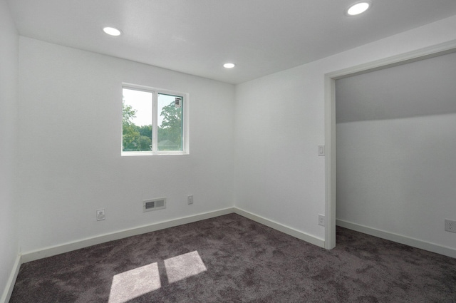 unfurnished bedroom with recessed lighting, visible vents, dark carpet, and baseboards