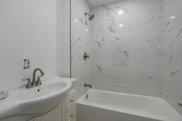 bathroom featuring bathtub / shower combination, vanity, and a textured wall