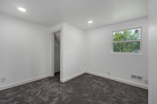 unfurnished bedroom featuring dark colored carpet, visible vents, baseboards, and recessed lighting