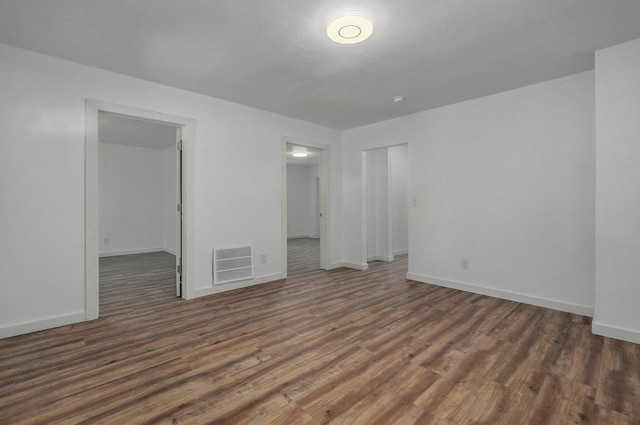 empty room featuring wood finished floors, visible vents, and baseboards