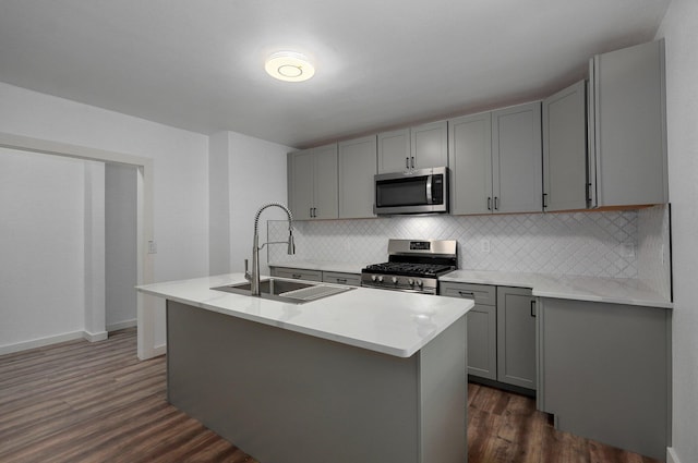 kitchen with gray cabinets, dark wood-style flooring, stainless steel appliances, and a sink