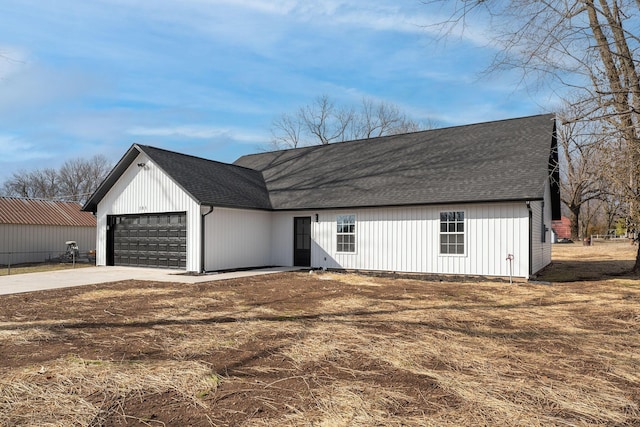 view of front of house featuring a garage, concrete driveway, and roof with shingles