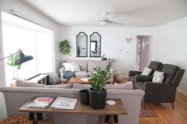 living room featuring a ceiling fan, baseboards, and wood finished floors