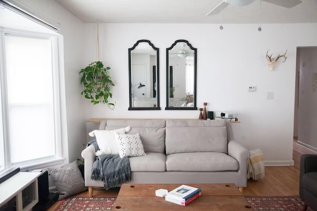 living area with ceiling fan, baseboards, and wood finished floors