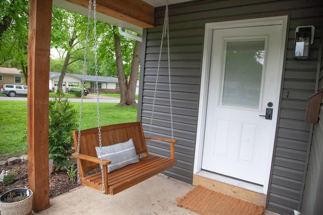 view of exterior entry with a porch and a lawn