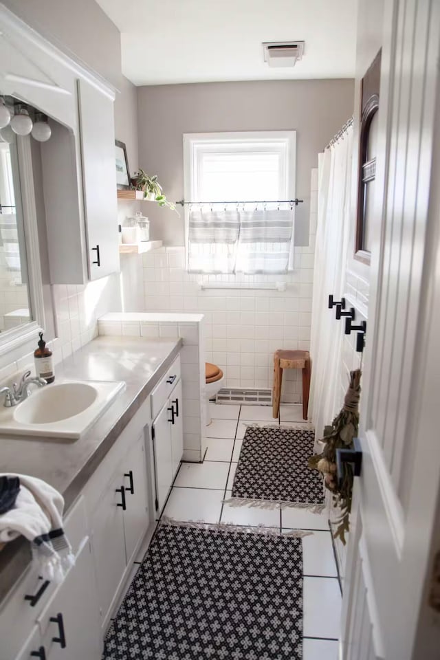 bathroom featuring tile walls, curtained shower, toilet, vanity, and tile patterned floors