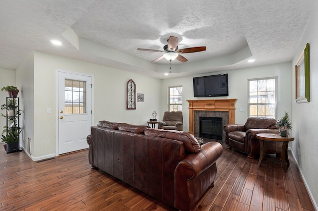 living room featuring dark wood-type flooring, a tray ceiling, a textured ceiling, and baseboards