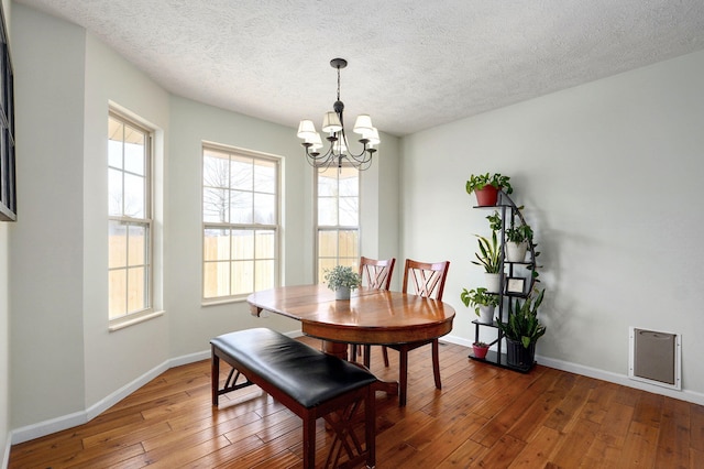 dining space featuring a chandelier, a textured ceiling, baseboards, and hardwood / wood-style flooring