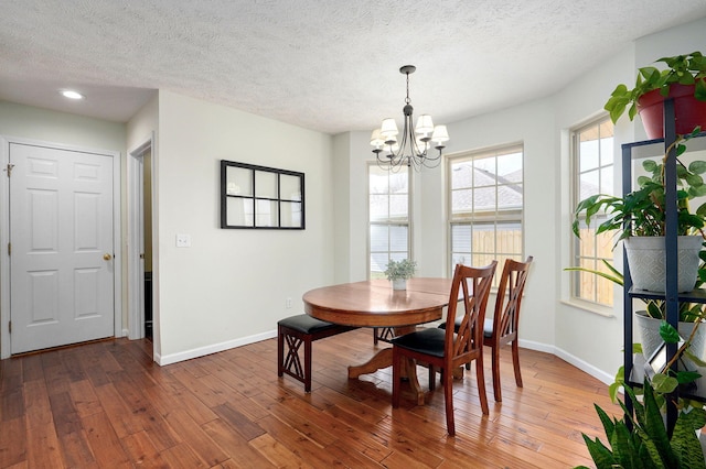 dining room with an inviting chandelier, a textured ceiling, baseboards, and hardwood / wood-style floors