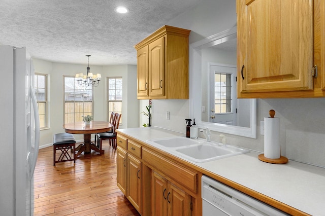 kitchen featuring white appliances, light wood finished floors, light countertops, a textured ceiling, and a sink