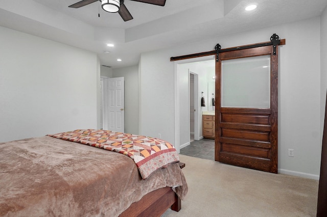 bedroom with a barn door, baseboards, a raised ceiling, carpet, and recessed lighting