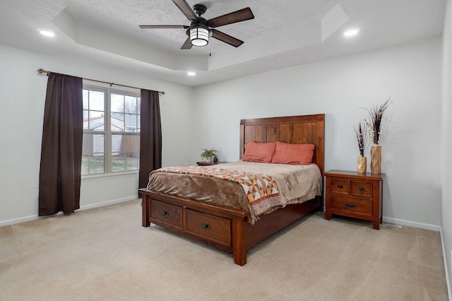 bedroom with light carpet, baseboards, a raised ceiling, and a textured ceiling