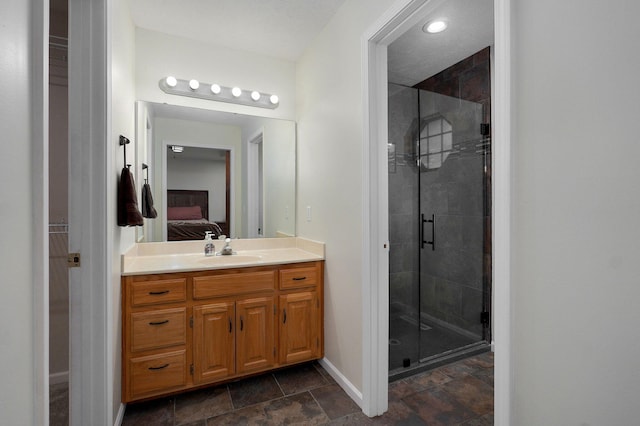 ensuite bathroom with a stall shower, baseboards, stone finish floor, ensuite bathroom, and vanity