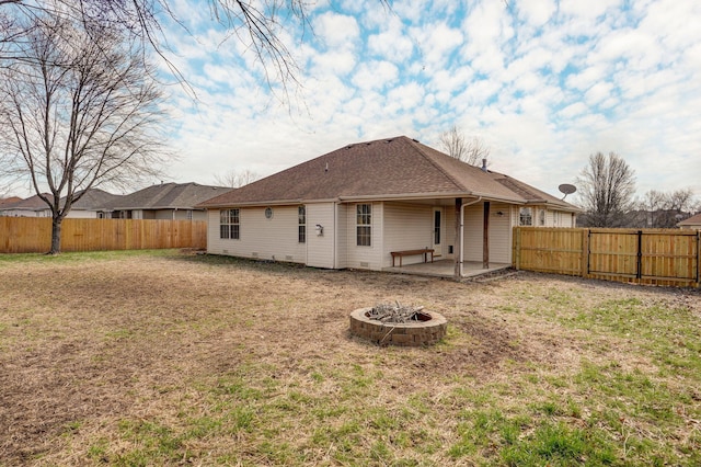 rear view of property with a patio area, a fenced backyard, a fire pit, and a lawn