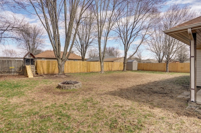 view of yard with an outbuilding, a playground, a storage shed, an outdoor fire pit, and a fenced backyard