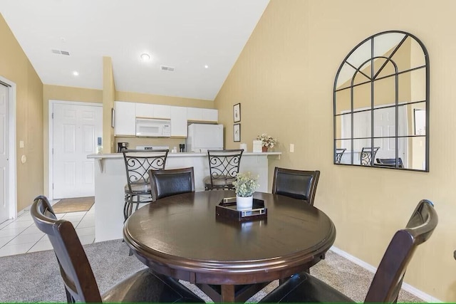 dining area with light tile patterned flooring, vaulted ceiling, visible vents, and baseboards