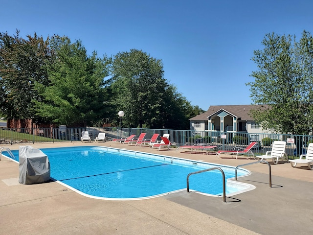 community pool with a patio area and fence