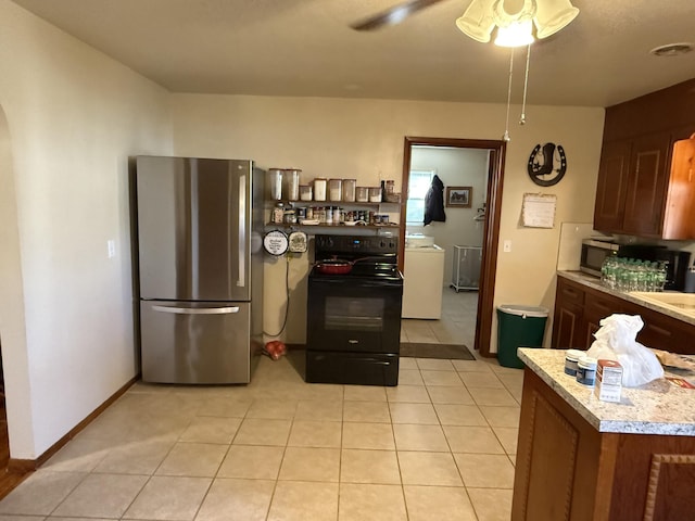 kitchen with light tile patterned floors, stainless steel appliances, washer / clothes dryer, light countertops, and baseboards