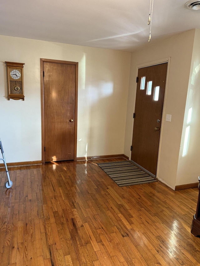 foyer entrance featuring baseboards, visible vents, and hardwood / wood-style floors