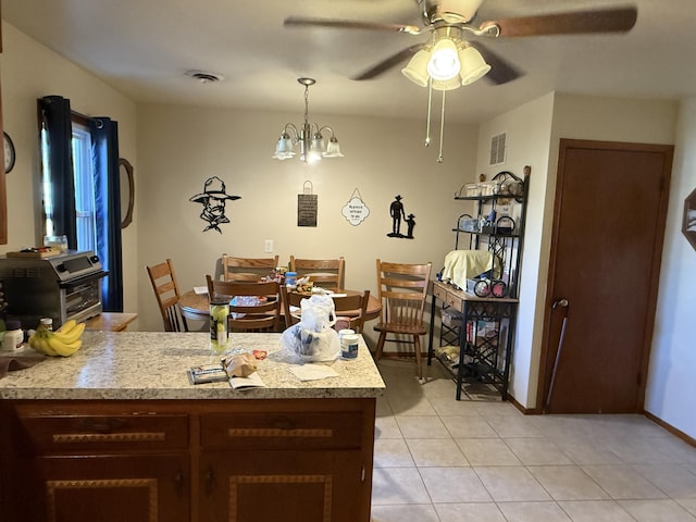 dining room with ceiling fan with notable chandelier, visible vents, baseboards, and light tile patterned floors