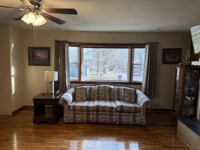 living area featuring ceiling fan, baseboards, and wood finished floors