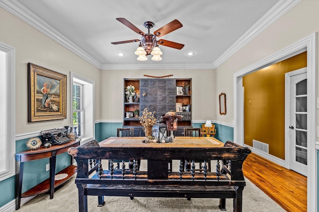 dining area featuring crown molding, visible vents, a ceiling fan, wood finished floors, and baseboards