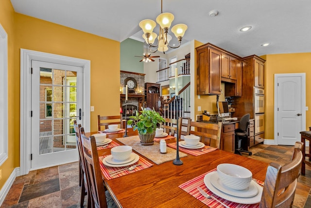 dining area with stone tile floors, baseboards, stairway, an inviting chandelier, and a brick fireplace