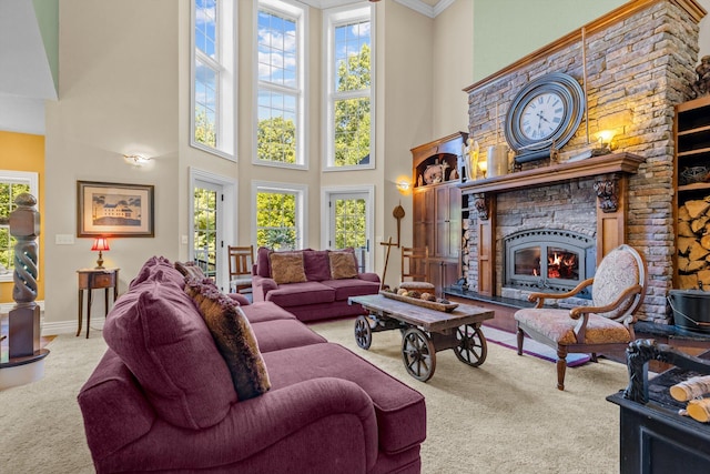 carpeted living area with a healthy amount of sunlight, a fireplace, and a towering ceiling