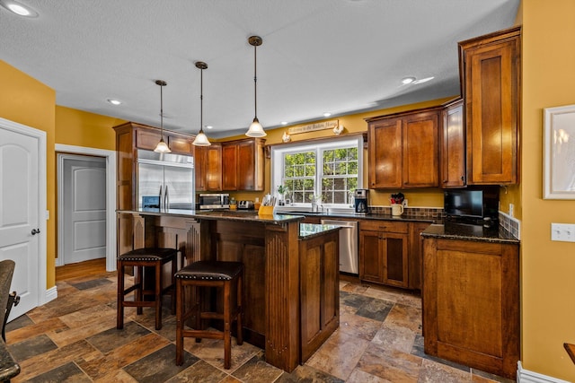 kitchen with a kitchen bar, appliances with stainless steel finishes, stone tile flooring, and a center island