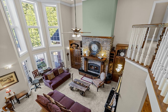 living room featuring a warm lit fireplace, stairway, ornamental molding, a high ceiling, and carpet flooring