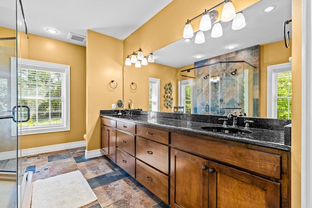 bathroom with a sink, visible vents, baseboards, a shower stall, and double vanity