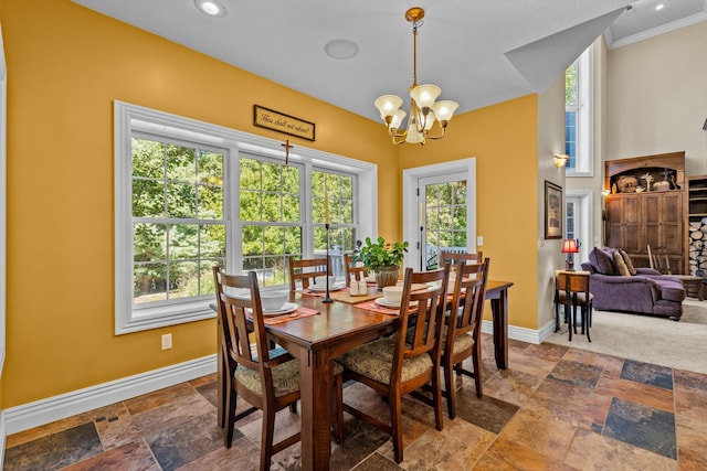 dining area with crown molding, an inviting chandelier, stone tile flooring, and baseboards