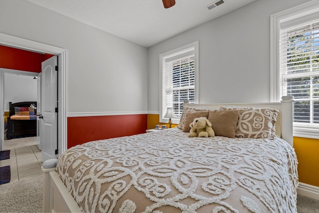 tiled bedroom featuring a ceiling fan, visible vents, and connected bathroom