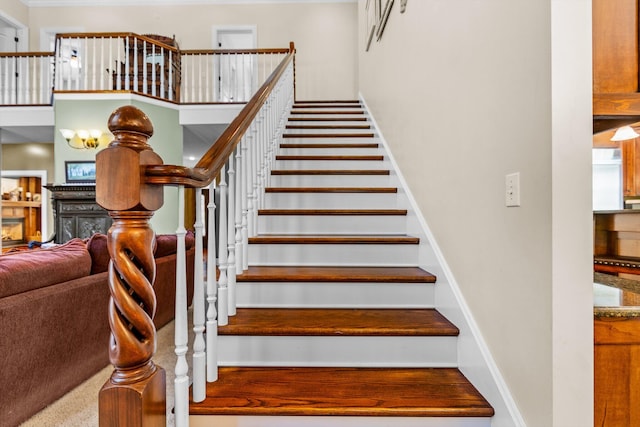 stairway with baseboards, a lit fireplace, and a high ceiling