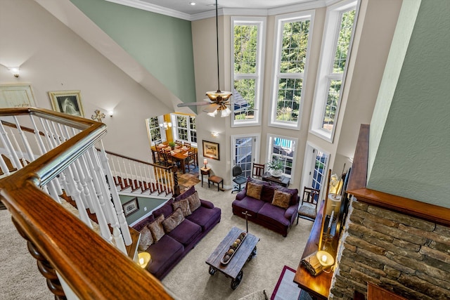 carpeted living area with ornamental molding, a high ceiling, and a ceiling fan