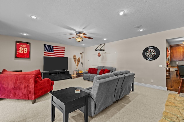 living room featuring a textured ceiling, ceiling fan, baseboards, and light colored carpet