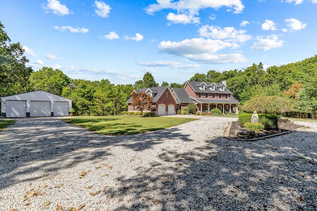 shingle-style home featuring an outbuilding, a view of trees, a garage, driveway, and a front lawn