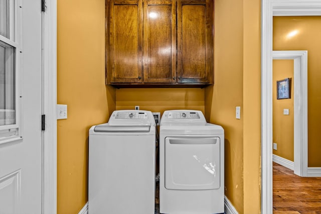 clothes washing area featuring cabinet space, baseboards, separate washer and dryer, and wood finished floors