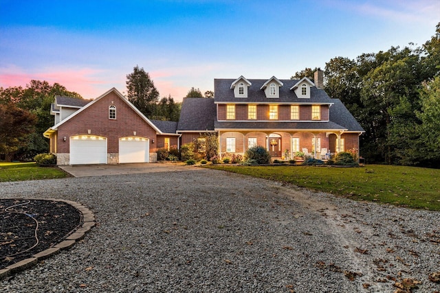 view of front of property with gravel driveway, brick siding, a garage, and a yard