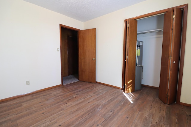 unfurnished bedroom featuring a closet, baseboards, a textured ceiling, and hardwood / wood-style floors