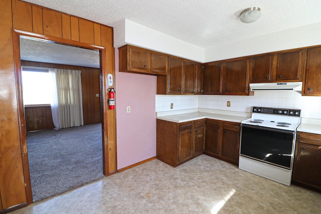 kitchen featuring white electric range oven, tasteful backsplash, light countertops, a textured ceiling, and under cabinet range hood