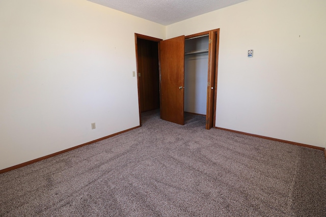 unfurnished bedroom featuring carpet floors, a closet, a textured ceiling, and baseboards